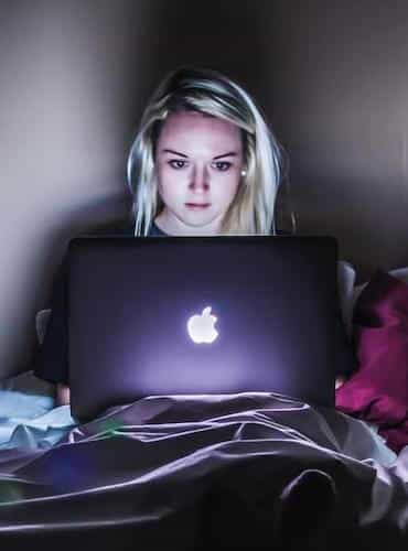 a workaholic working on her computer in bed