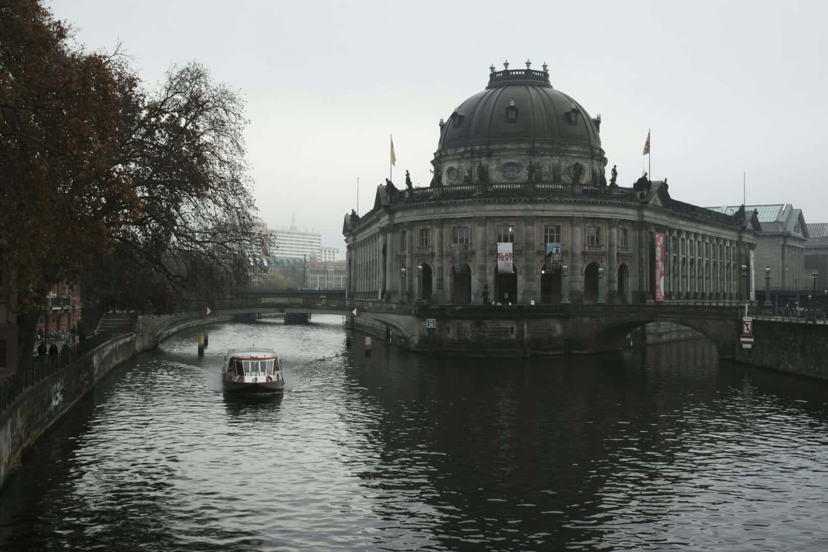 boat traveling down a river next to large building
